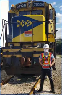 MRS Logistica Com operador em frente a um trem amarelo e azul