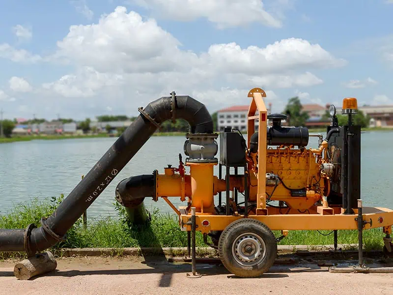 yellow diesel engine water pump next to a pond